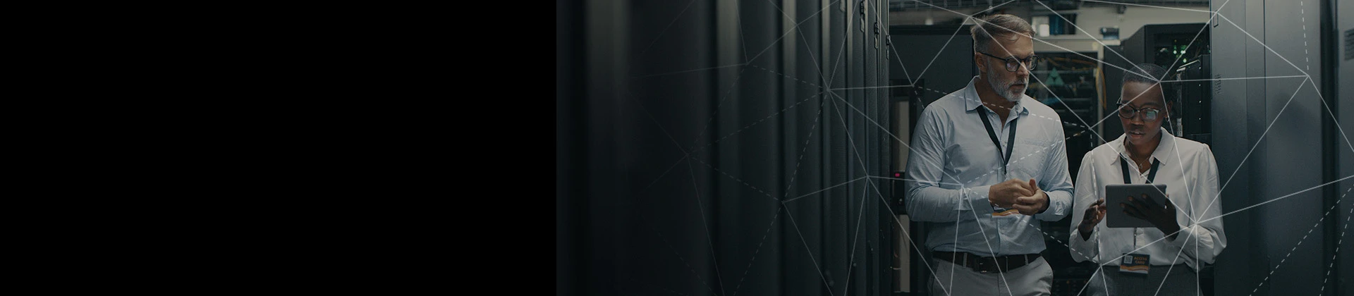 photo of man and woman walking in between rows of towers in a server room 