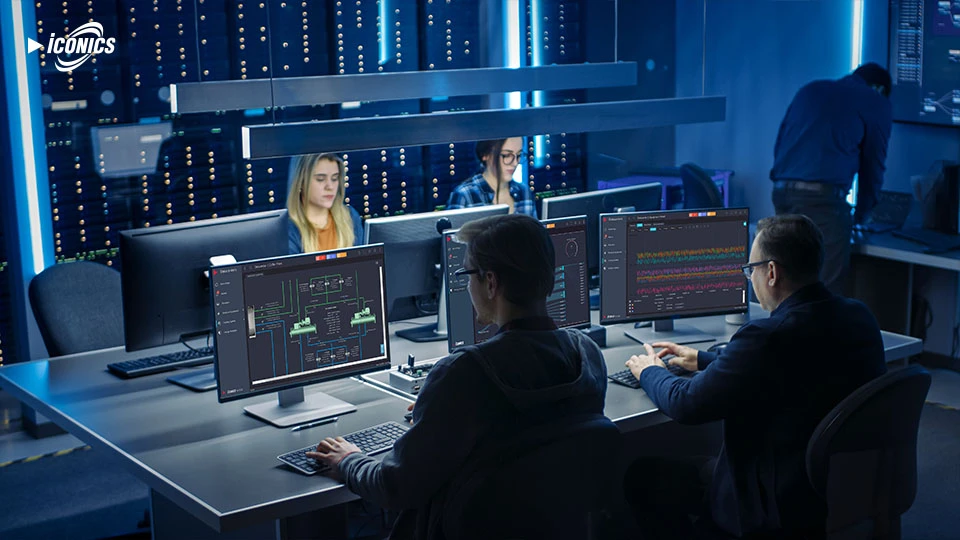 Photo of four people working at desktops in a server room, with an instructor off to the right, slightly out of focus